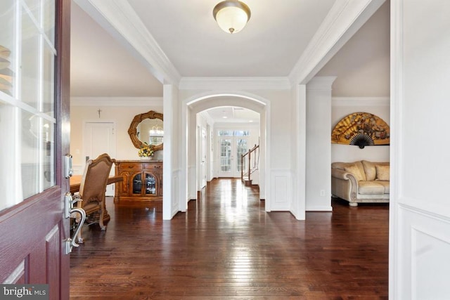 foyer with arched walkways, dark wood-type flooring, and crown molding