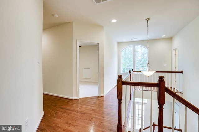hall featuring an upstairs landing, wood finished floors, baseboards, and recessed lighting