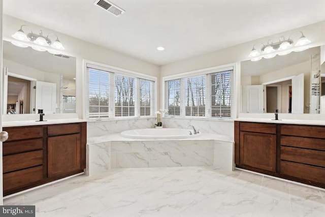 full bathroom featuring marble finish flooring, a garden tub, and two vanities