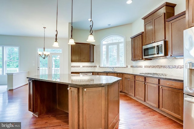 kitchen featuring stainless steel appliances, a sink, a kitchen island, hardwood / wood-style floors, and a chandelier