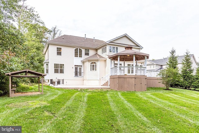 rear view of property featuring a gazebo, a lawn, and a patio area