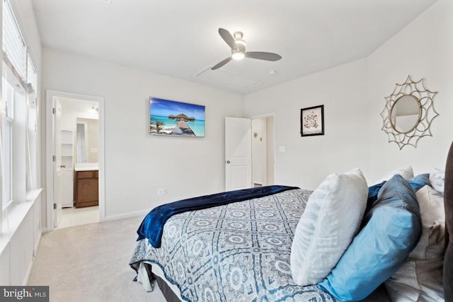 bedroom featuring light colored carpet, ensuite bath, and a ceiling fan