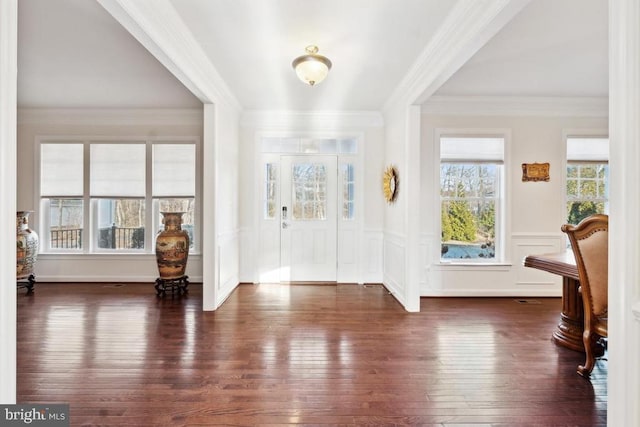 entrance foyer featuring hardwood / wood-style floors, crown molding, a wainscoted wall, and a decorative wall