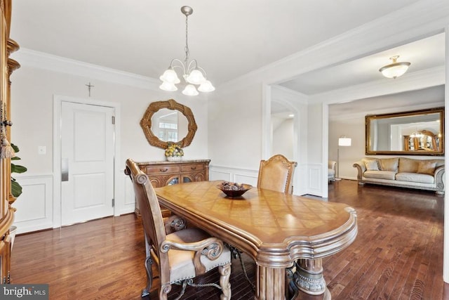dining room featuring a chandelier, a decorative wall, ornamental molding, wood finished floors, and wainscoting