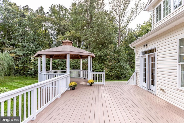 wooden deck with a gazebo and view of wooded area