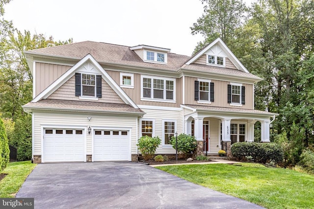 view of front facade with driveway, a front lawn, a porch, board and batten siding, and a shingled roof