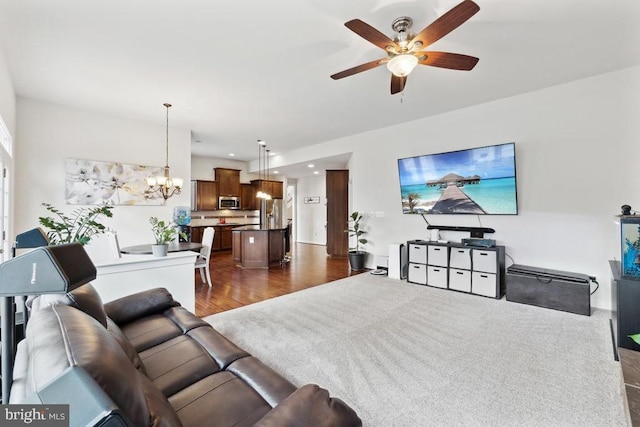 living room with a ceiling fan, a chandelier, and dark wood-style flooring