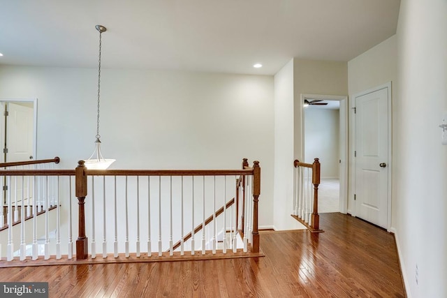 hall with an upstairs landing, wood finished floors, recessed lighting, and baseboards