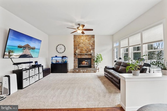 living room featuring a ceiling fan and a stone fireplace