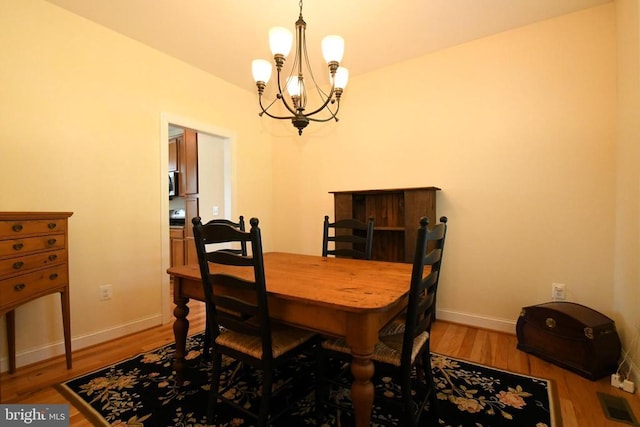 dining area with an inviting chandelier, baseboards, wood finished floors, and visible vents