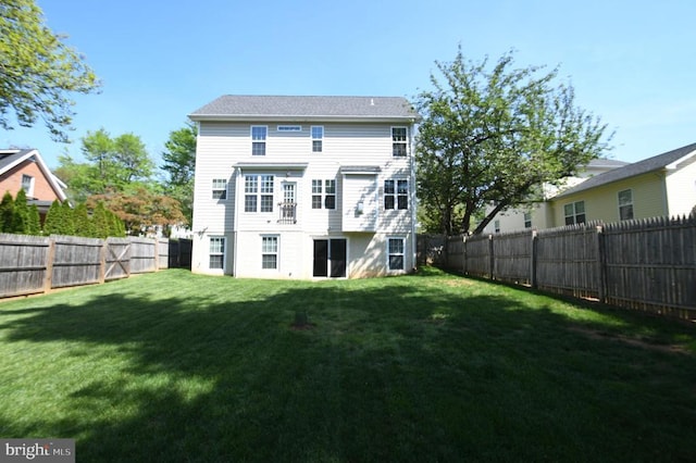 rear view of property featuring a lawn and a fenced backyard