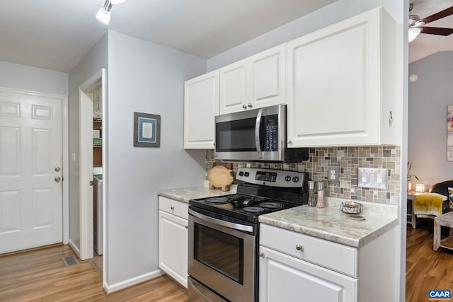 kitchen featuring stainless steel appliances, white cabinetry, light countertops, light wood-style floors, and tasteful backsplash