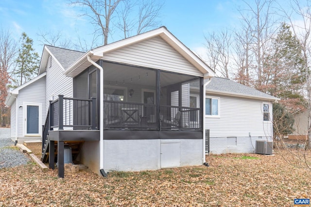 view of side of property with central air condition unit, a sunroom, and a shingled roof