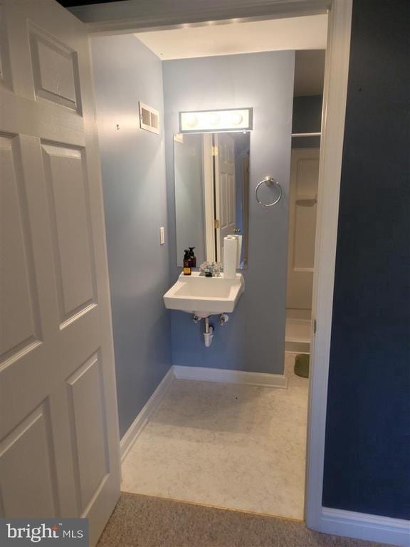 bathroom with a shower, baseboards, and a sink