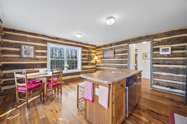 kitchen featuring dark wood-type flooring, log walls, wooden walls, a center island, and stainless steel dishwasher