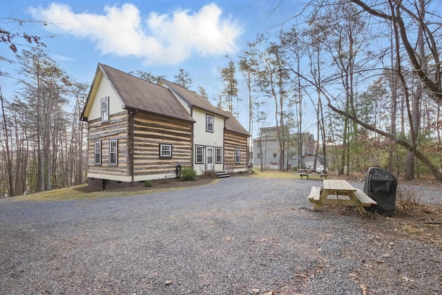 view of property exterior with driveway, log exterior, and crawl space