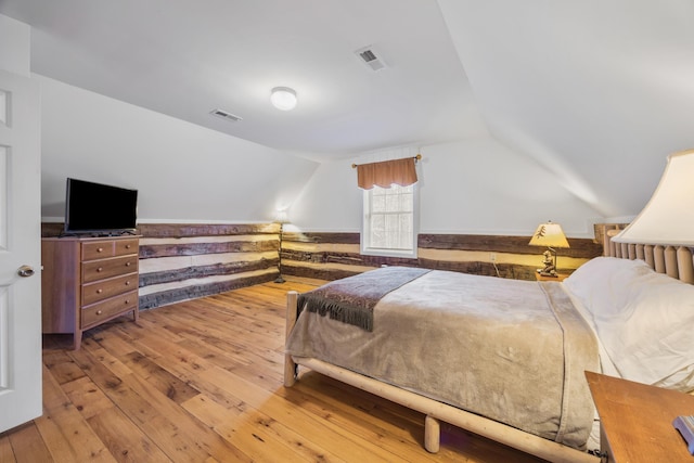 bedroom with vaulted ceiling, hardwood / wood-style flooring, and visible vents