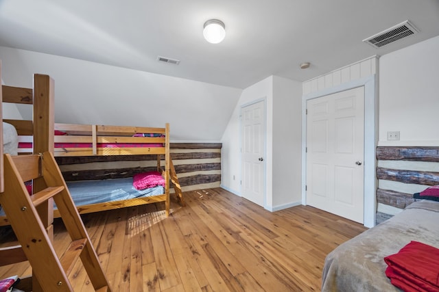 bedroom featuring vaulted ceiling, visible vents, baseboards, and hardwood / wood-style flooring