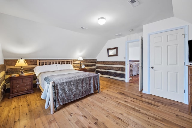 bedroom featuring light wood-style flooring, visible vents, and vaulted ceiling