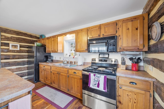 kitchen featuring a sink, brown cabinetry, dark wood finished floors, black appliances, and light countertops