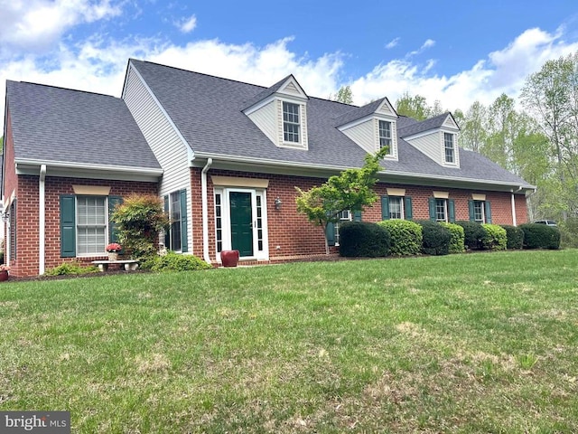 cape cod home featuring brick siding and a front yard