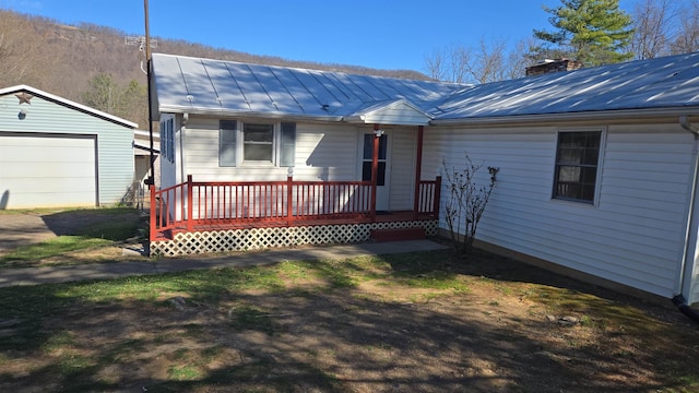 single story home with a chimney, metal roof, a standing seam roof, and covered porch