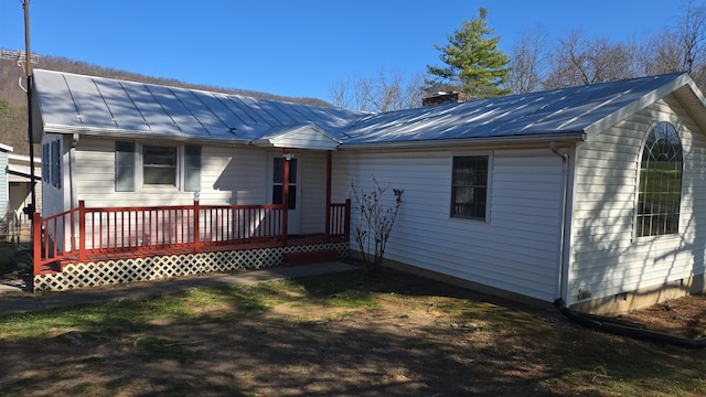 rear view of property with a chimney, metal roof, and a standing seam roof