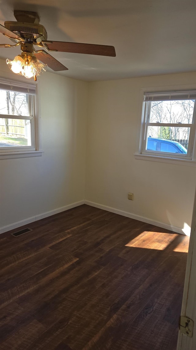 unfurnished room featuring ceiling fan, baseboards, a healthy amount of sunlight, and dark wood-style floors
