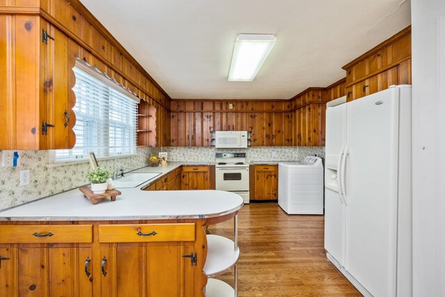kitchen featuring washer / clothes dryer, white appliances, a sink, light countertops, and a peninsula