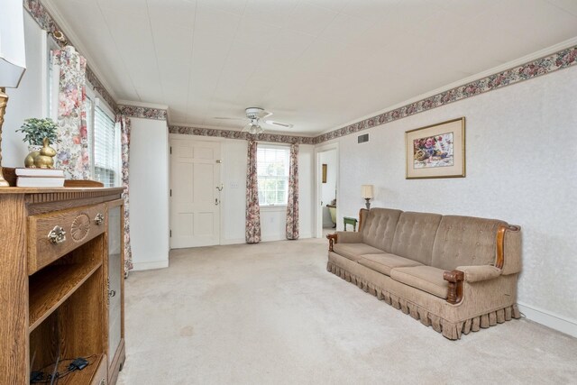 living area with ceiling fan, carpet flooring, ornamental molding, and baseboards