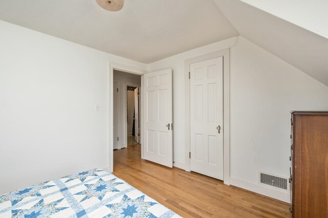 unfurnished bedroom featuring light wood-style floors and vaulted ceiling