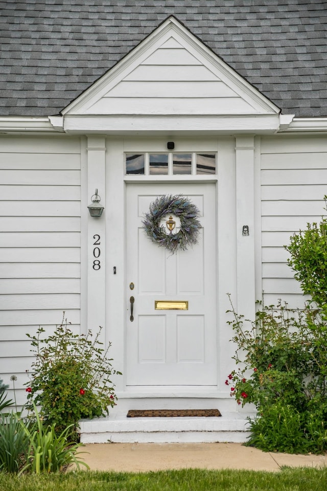 view of exterior entry with a shingled roof