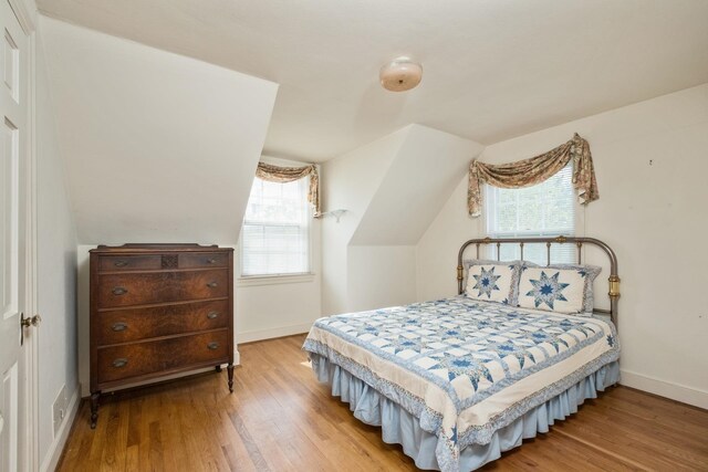 bedroom featuring wood finished floors, multiple windows, and baseboards