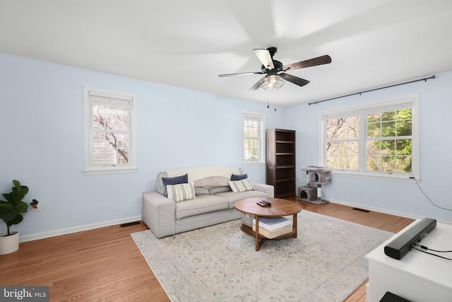 living area with baseboards, plenty of natural light, and wood finished floors