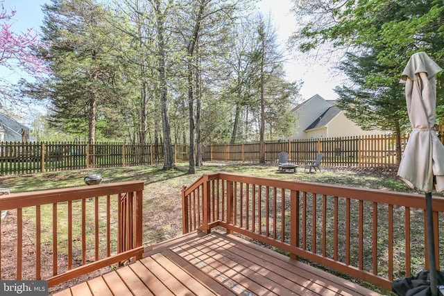 wooden terrace with a fenced backyard and a fire pit