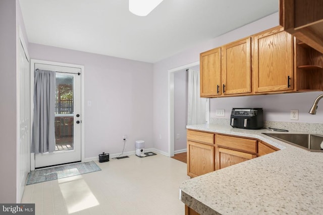 kitchen featuring visible vents, open shelves, baseboards, light countertops, and a sink