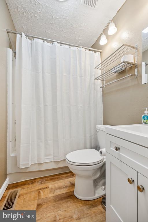 10603 Bluebird Ln, Spotsylvania, VA 22553 - bathroom with vanity, wood finished floors, shower / bath combo, and a textured ceiling
