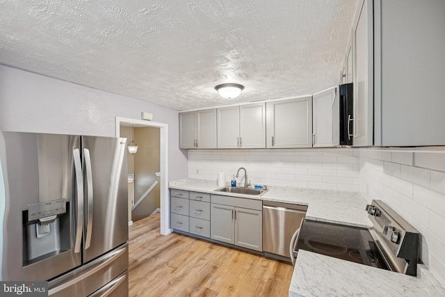 10603 Bluebird Ln, Spotsylvania, VA 22553 - kitchen featuring appliances with stainless steel finishes, gray cabinetry, a textured ceiling, light wood-style floors, and tasteful backsplash