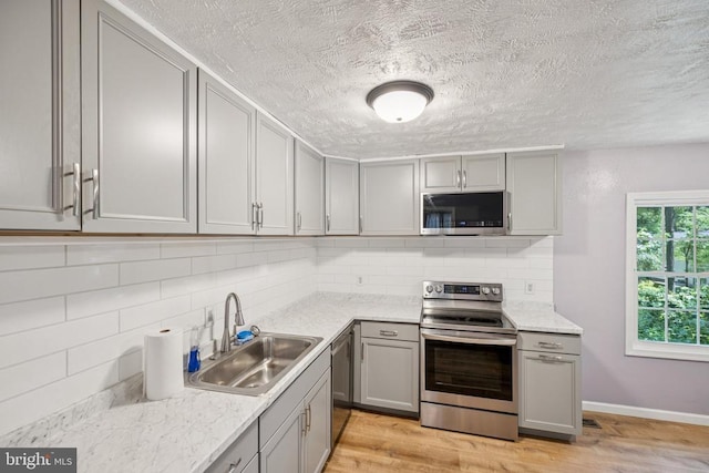 10603 Bluebird Ln, Spotsylvania, VA 22553 - kitchen featuring stainless steel appliances, gray cabinets, backsplash, light wood-style flooring, and a textured ceiling