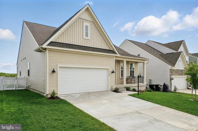 craftsman-style house featuring board and batten siding, covered porch, driveway, and a shingled roof