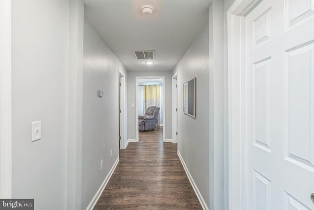 corridor with dark wood-style flooring, baseboards, and visible vents
