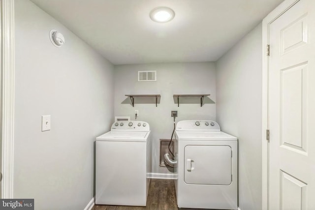 laundry area with wood finished floors, laundry area, visible vents, washing machine and clothes dryer, and baseboards