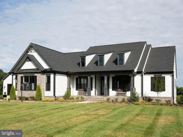 view of front of house with covered porch, a front lawn, and a shingled roof