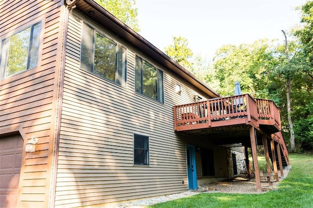 rear view of property featuring a yard, a wooden deck, and a garage