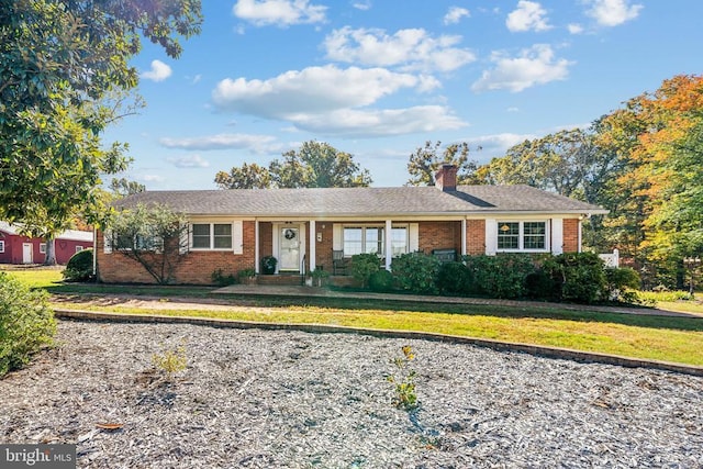 single story home featuring brick siding, a front lawn, and a chimney