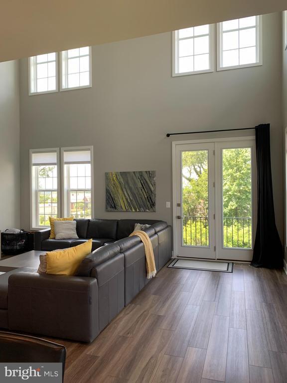  - living room featuring a towering ceiling and wood finished floors