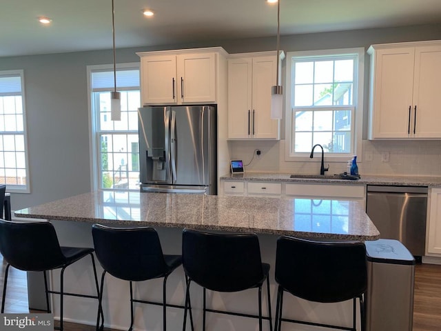  - kitchen featuring stainless steel appliances, recessed lighting, white cabinets, a kitchen breakfast bar, and a kitchen island