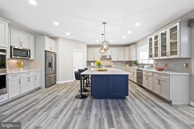 7806 Shawmont Rd, Fredericksburg, VA 22407 - kitchen with stainless steel appliances, decorative backsplash, light wood finished floors, under cabinet range hood, and a breakfast bar area