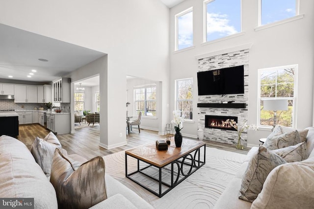 7806 Shawmont Rd, Fredericksburg, VA 22407 - living room with a towering ceiling, light wood-type flooring, healthy amount of natural light, a fireplace, and baseboards
