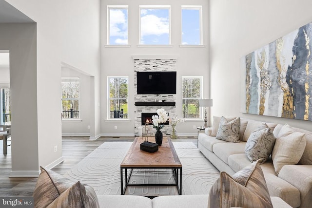7806 Shawmont Rd, Fredericksburg, VA 22407 - living room with a towering ceiling, wood finished floors, plenty of natural light, baseboards, and a warm lit fireplace